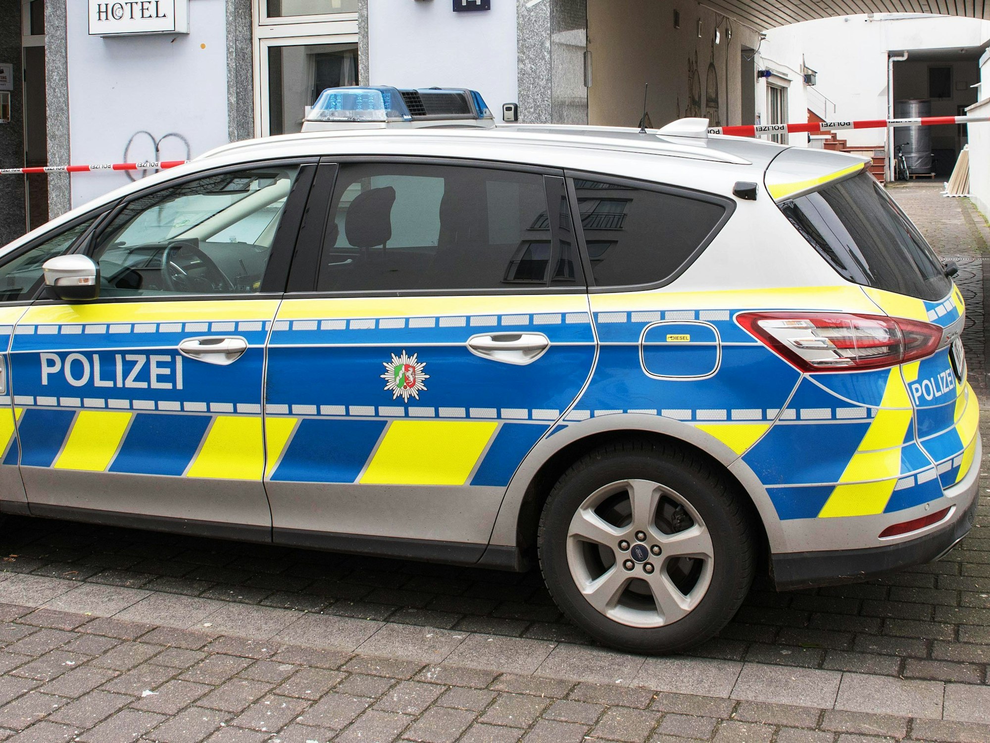Ein Polizeiauto steht vor dem Hotel in Köln-Kalk, in dem am Samstag (11. März 2023) zwei schwer verletzte Männer gefunden wurden. Beide kamen mit Schnittverletzungen in Krankenhäuser.