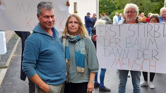 Einige Menschen protestieren mit Plakaten gegen den Bau eines Feriendorfs am Freilinger See.