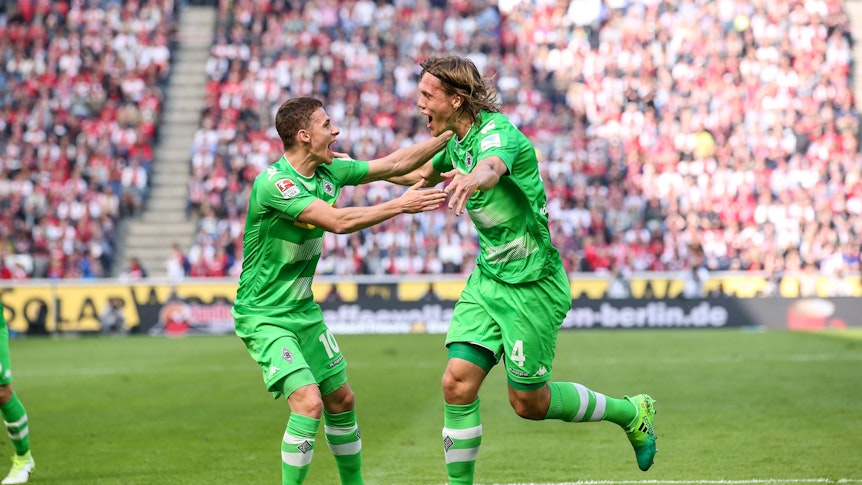 Jannik Vestergaard (r.) bejubelt am 8. April 2017 gemeinsam mit seinem damaligen Teamkollegen Thorgan Hazard ein Tor von Borussia Mönchengladbach beim 1. FC Köln. Sie tragen ein knallgrünes Gladbach-Trikot, Vestergaard schreit seine Freude beim Torjubel heraus.