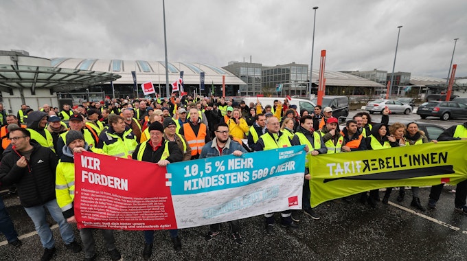 Mitarbeiterinnen und Mitarbeiter verschiedener Firmen streiken am Airport Hamburg kommen auf einem Parkdeck.