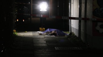 Die Leiche des 23-Jährigen liegt mit einem blauen Tuch abgedeckt auf dem Asphalt.