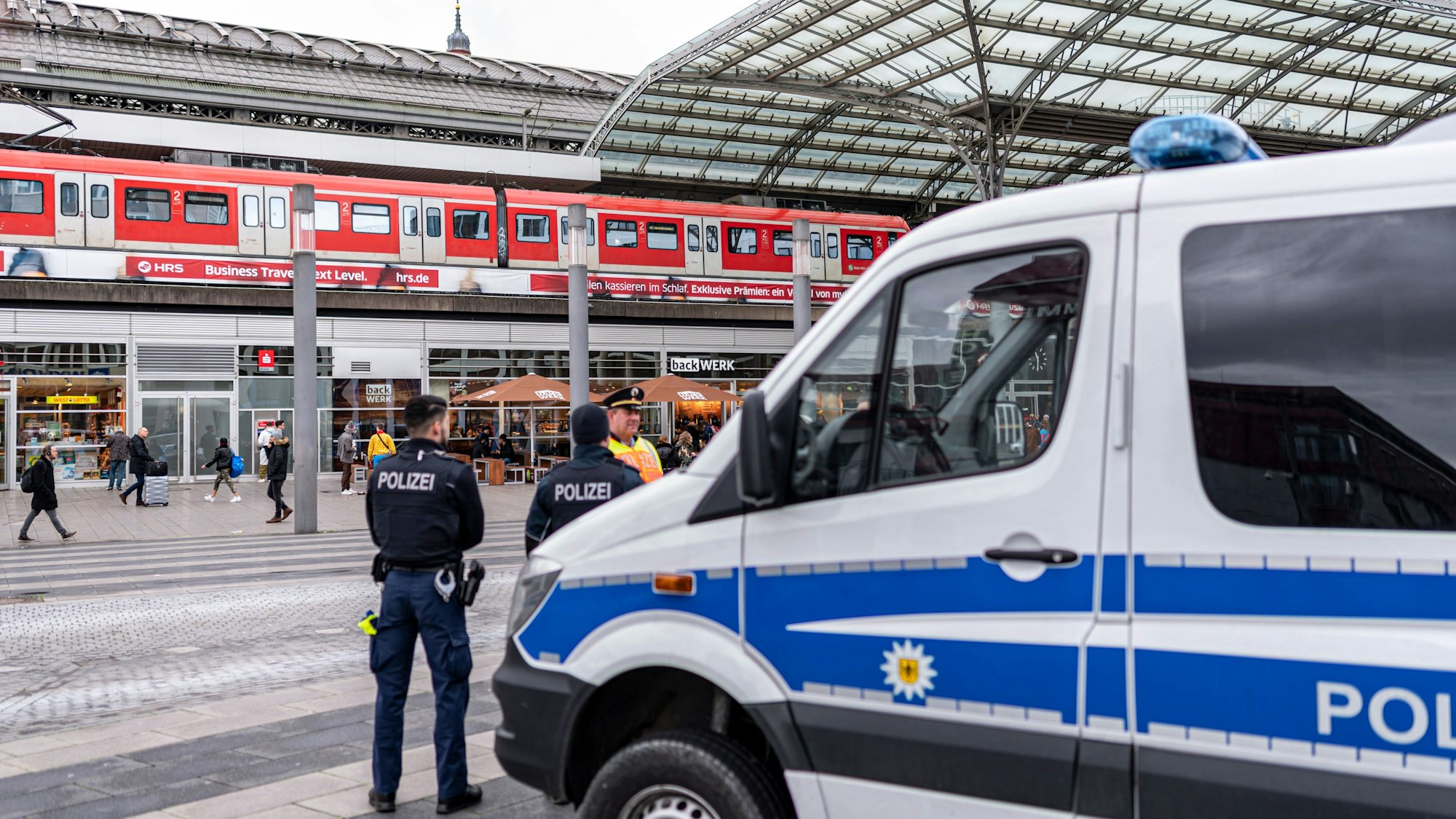 Ein Polizei-Auto und mehrere Beamte stehen vor dem Kölner Hauptbahnhof.