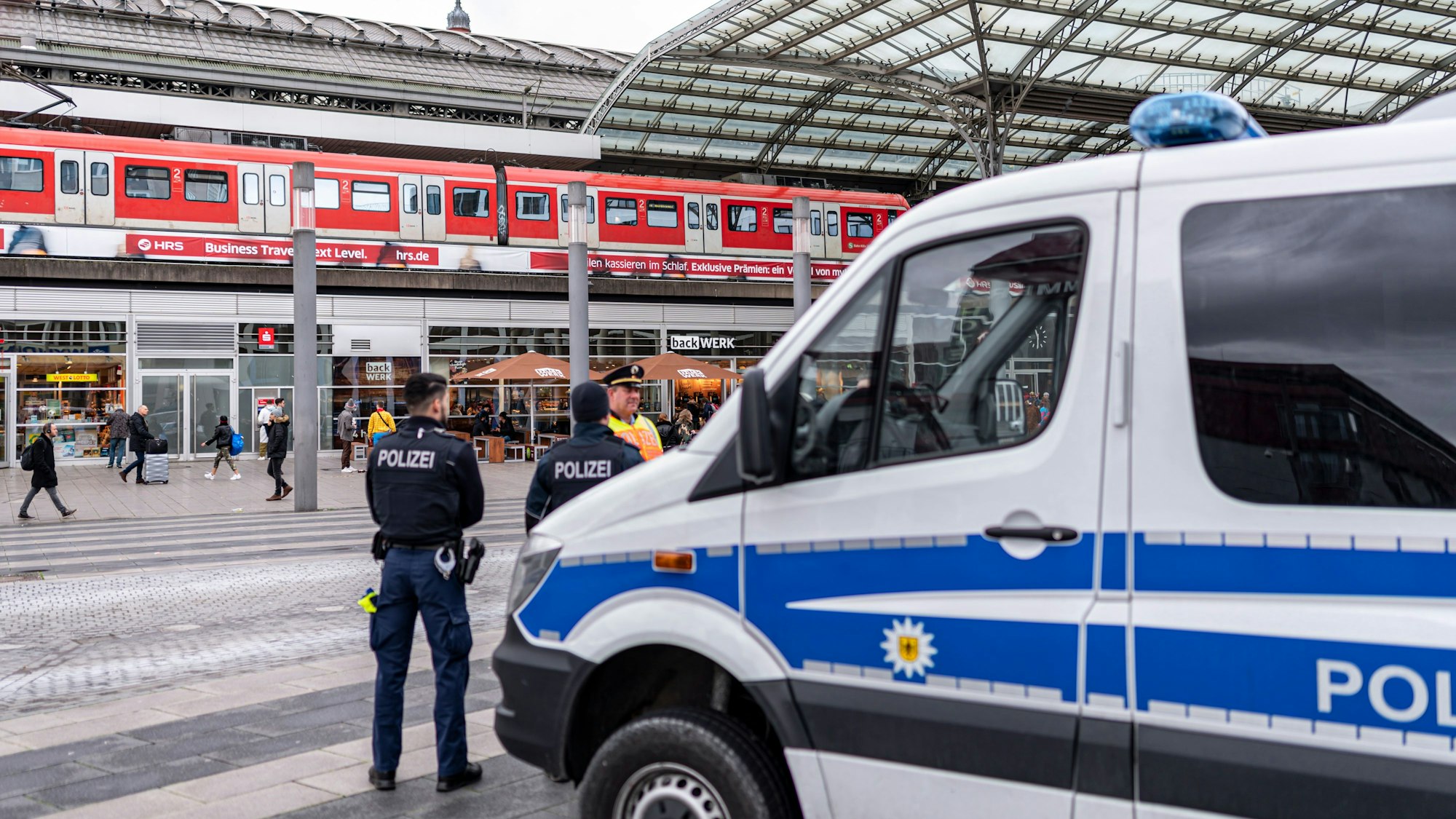 Ein Polizei-Auto und mehrere Beamte stehen vor dem Kölner Hauptbahnhof.