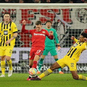 Jude Bellingham (r.) und Florian Wirtz im Spiel zwischen Bayer Leverkusen und Borussia Dortmund im Zweikampf.