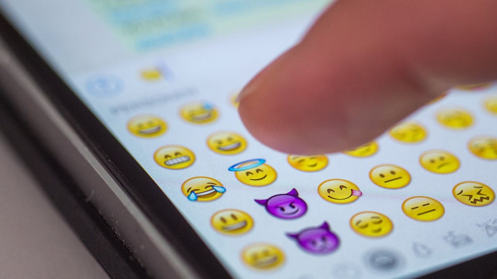 Eine Frau tippt am 24.08.2015 in München (Bayern) auf das Display eines Smartphones, auf dem zahlreiche Emojis in der Nachrichten-App „Whatsapp“ zu sehen sind.