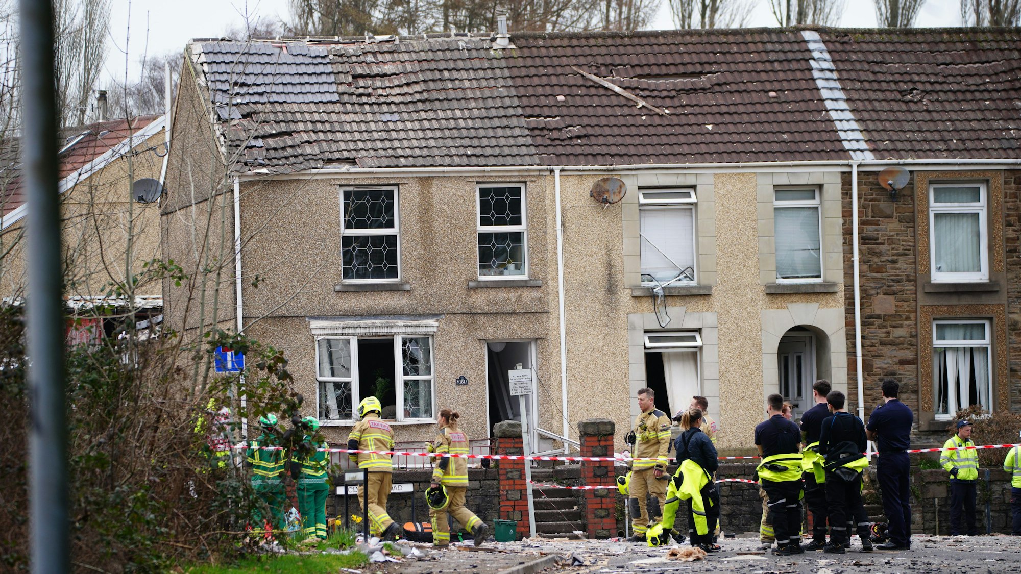 Einsatzkräfte stehen nach einer schweren Detonation vor zwei zerstörten Häusern an einer Straßenkreuzung in Morriston.