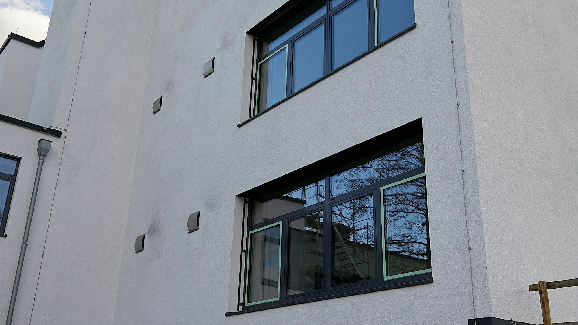 An der weißen Fassade der Hauptschule Hellenthal sind graue Stellen zu sehen, die offenbar durch Algen verursacht werden.