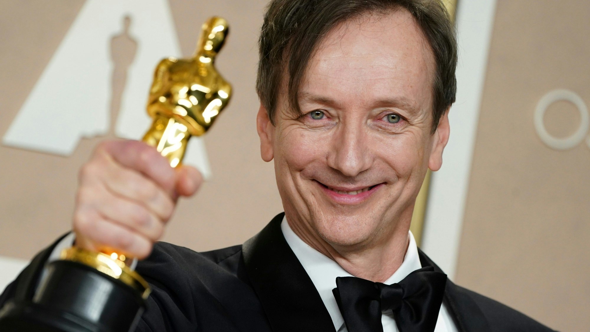 Komponist Volker Bertelmann hält am Sonntagabend in Los Angeles seinen Oscar für die beste Filmmusik für „Im Westen nichts Neues“ hoch.