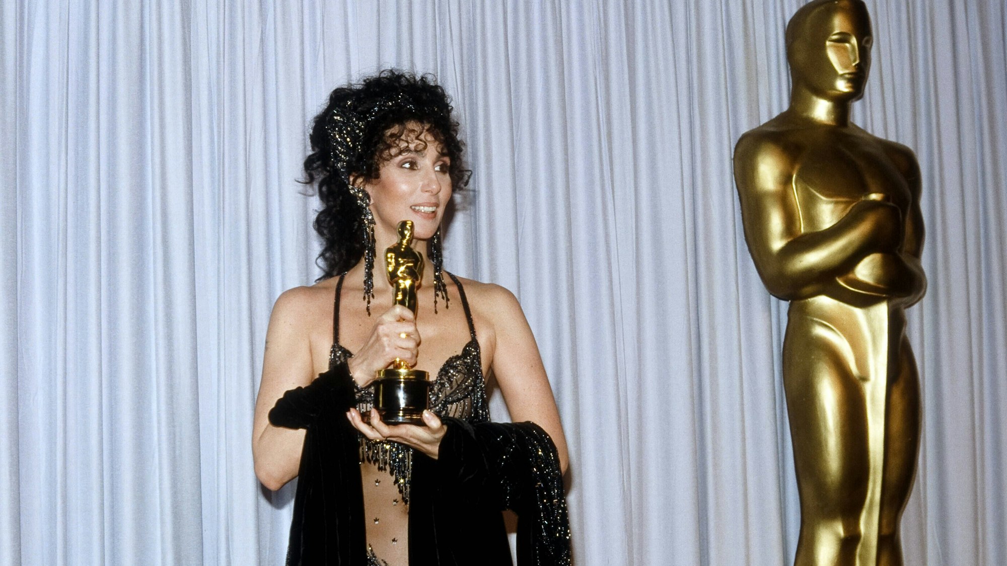 Cher hält ihren Oscar in Händen.