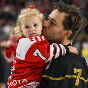 Nick Bailen (Kölner Haie) mit seiner Tochter auf dem Arm bei der Ehrenrunde gegen die Bietigheim Steelers.