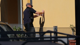 Ein Ermittler zieht ein Projektil aus einer Hauswand am Tatort.