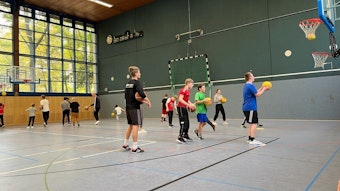 Basketballtraining bei der „Bananenflanke“ in einer Halle der Deutschen Sporthochschule Köln: Viele Kinder sind zu sehen, die mit gelben Bällen Basketball trainieren.