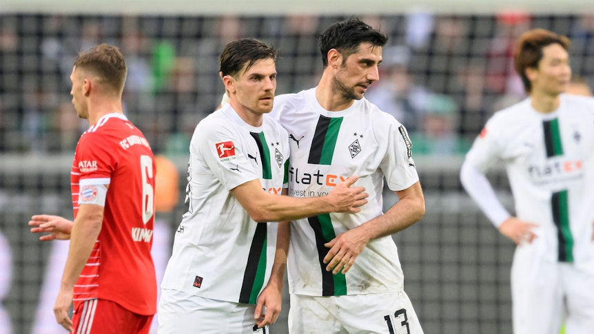 Jonas Hofmann (l.) jubelt nach dem Bundesliga-Sieg von Borussia Mönchengladbach gegen Bayern München am 18. Februar 2023 gemeinsam mit Mitspieler Lars Stindl. Die beiden Gladbach-Spieler liegen sich nach Abpfiff im Borussia-Park in den Armen.
