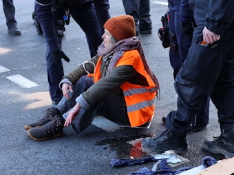 Eine Klima-Aktivistin wird von der Polizei von der Fahrbahn auf der Aachener Str. gelöst.