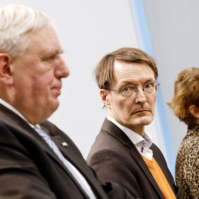 Links steht Laumann bei einer Pressekonderenz, sein Bild ist leicht verschwommen. Lauterbach steht rechts daneben, die Kamera fokussiert auf ihn. Lauterbach blickt auf Laumann.