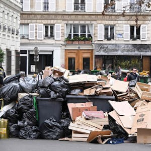 Müll stapelt sich auf und vor den Hausmüllcontainern in einer Pariser Straße.