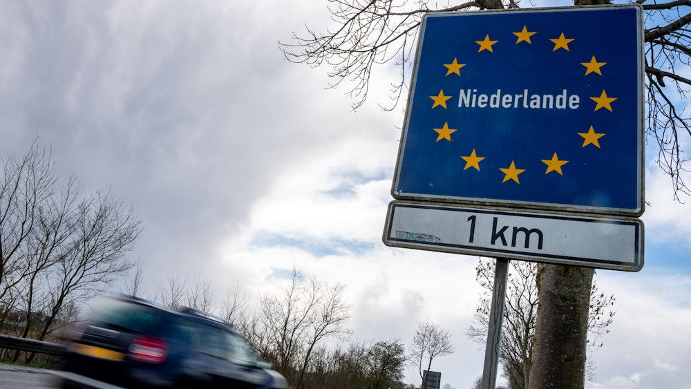 Ein Pkw fährt an einem Schild vorbei, das auf die deutsch-niederländische Grenze hinweist.