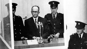 Der NS-Kriegsverbrecher Adolf Eichmann (2.v.l.) vor dem Bezirksgericht in Jerusalem. Eichmann befindet sich, von drei uniformierten Beamten bewacht, auf dem verglasten Platz des Angeklagten. Das Archivfoto stammt vom 11. April 1961.