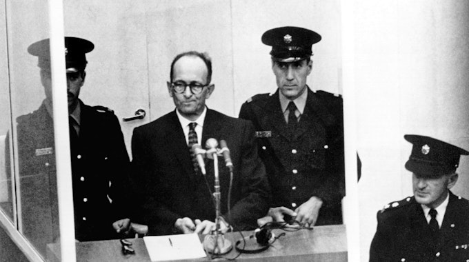 Der NS-Kriegsverbrecher Adolf Eichmann (2.v.l.) vor dem Bezirksgericht in Jerusalem. Eichmann befindet sich, von drei uniformierten Beamten bewacht, auf dem verglasten Platz des Angeklagten. Das Archivfoto stammt vom 11. April 1961.