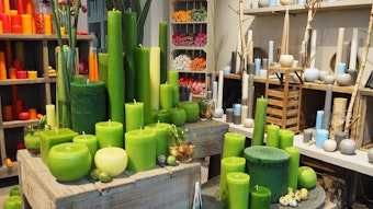 Kerzen aus verschiedenen Grün- und Orangetönen in einem Laden mit Holzeinrichtung