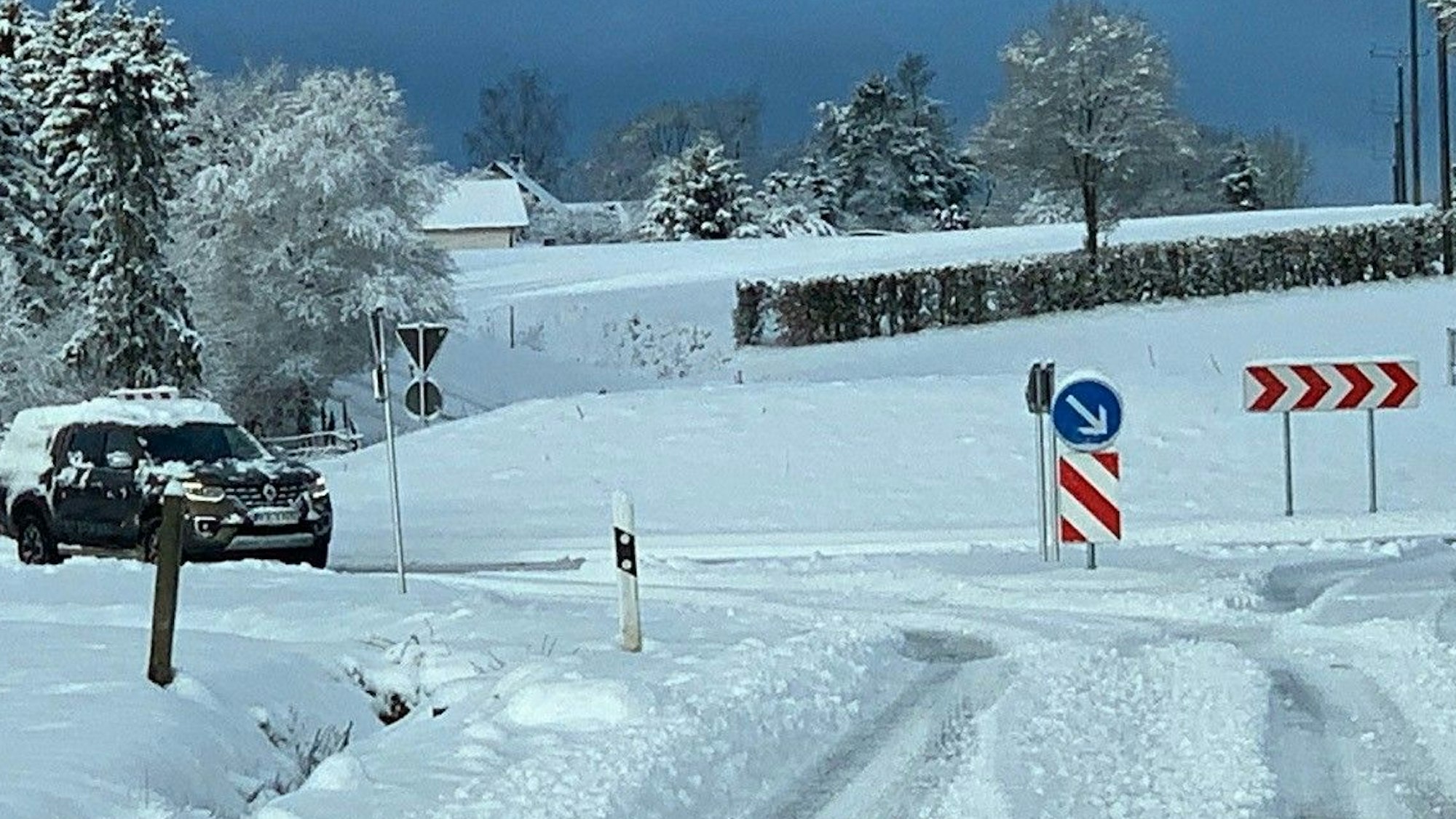 Ein Auto fährt auf eine Kreuzug zu. Die Fahrbahn ist mit Schnee bedeckt.