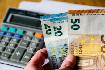 Taschenrechner und Euro-Scheine in einer Hand