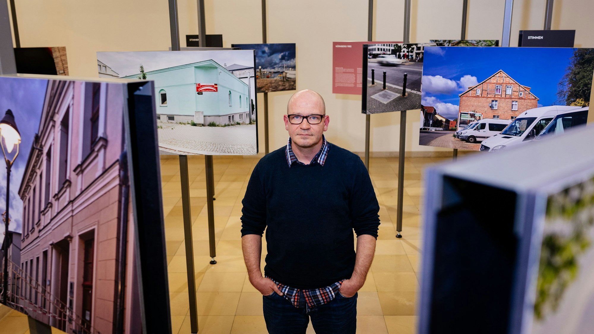 Der Fotograf Mark Mühlhaus steht mit Händen in den Hosentaschen in der Ausstellung im NS-Dokumentationszentrum in Köln.