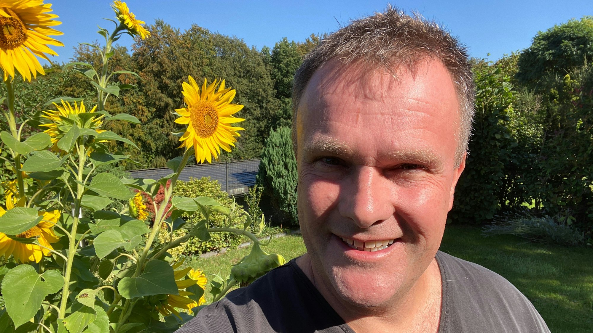 Torsten Brämer steht neben Sonnenblumen in seinem Garten in Odenthal.