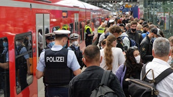 Polizei und Mitarbeiter der Deutschen Bahn weisen Reisenden auf einem überfülltem Bahnsteig im Hauptbahnhof den Weg.