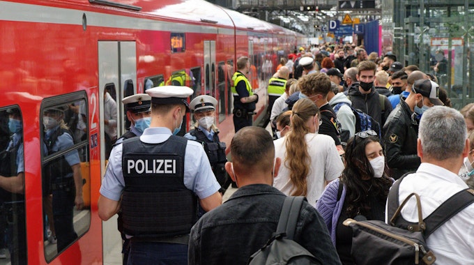 Polizei und Mitarbeiter der Deutschen Bahn weisen Reisenden auf einem überfülltem Bahnsteig im Hauptbahnhof den Weg.
