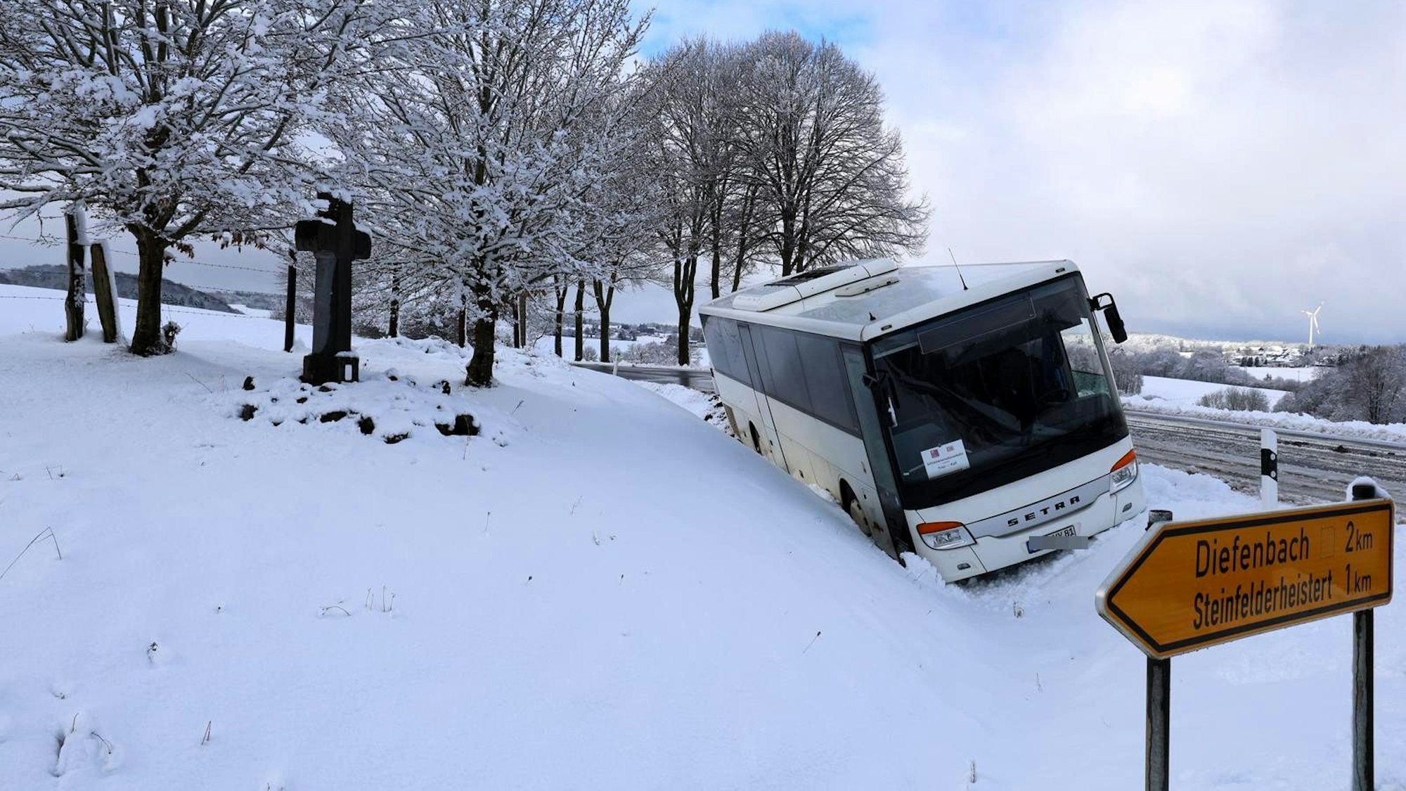 Ein Bus steht schräg in einem Graben. Die Landschaft ist verschneit.