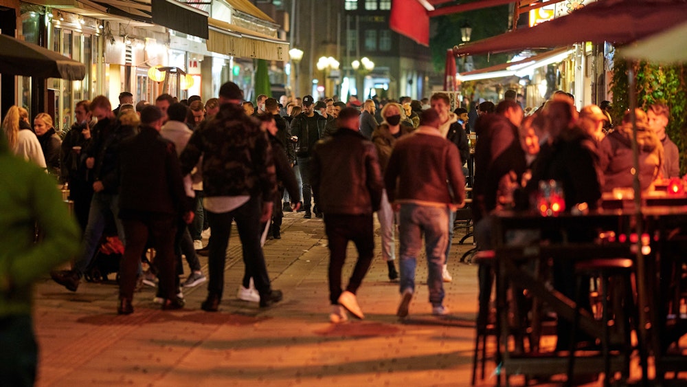 Menschen bummeln abends durch die Düsseldorfer Altstadt, einige sitzen draußen vor einer Gaststätte.