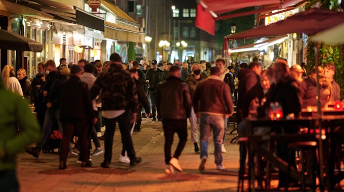 Menschen bummeln abends durch die Düsseldorfer Altstadt, einige sitzen draußen vor einer Gaststätte.