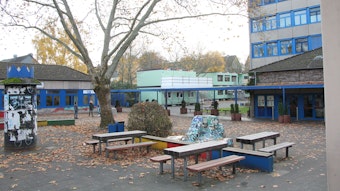 Man sieht den Schulhof, im Hintergrund Container und das Schulgebäude.