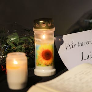 Zwei Kerzen und eine Trauerkarte stehen auf einem Tisch.