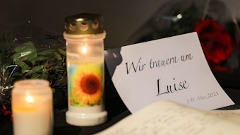 Ein Kondolenzbuch liegt neben Blumen und Kerzen in einer Kirche aus.
