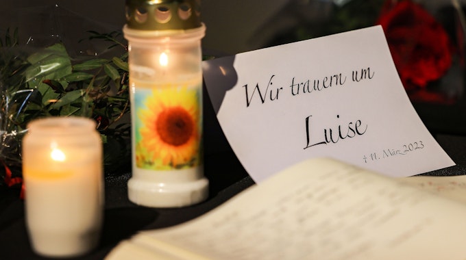 Ein Kondolenzbuch liegt neben Blumen und Kerzen in einer Kirche aus.&nbsp;