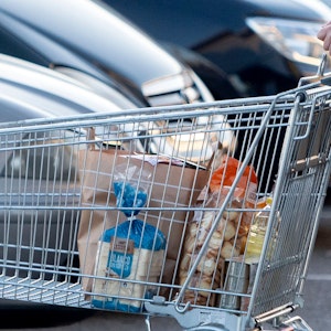 Eine Frau verlässt einen Supermarkt mit einem Einkaufswagen.
