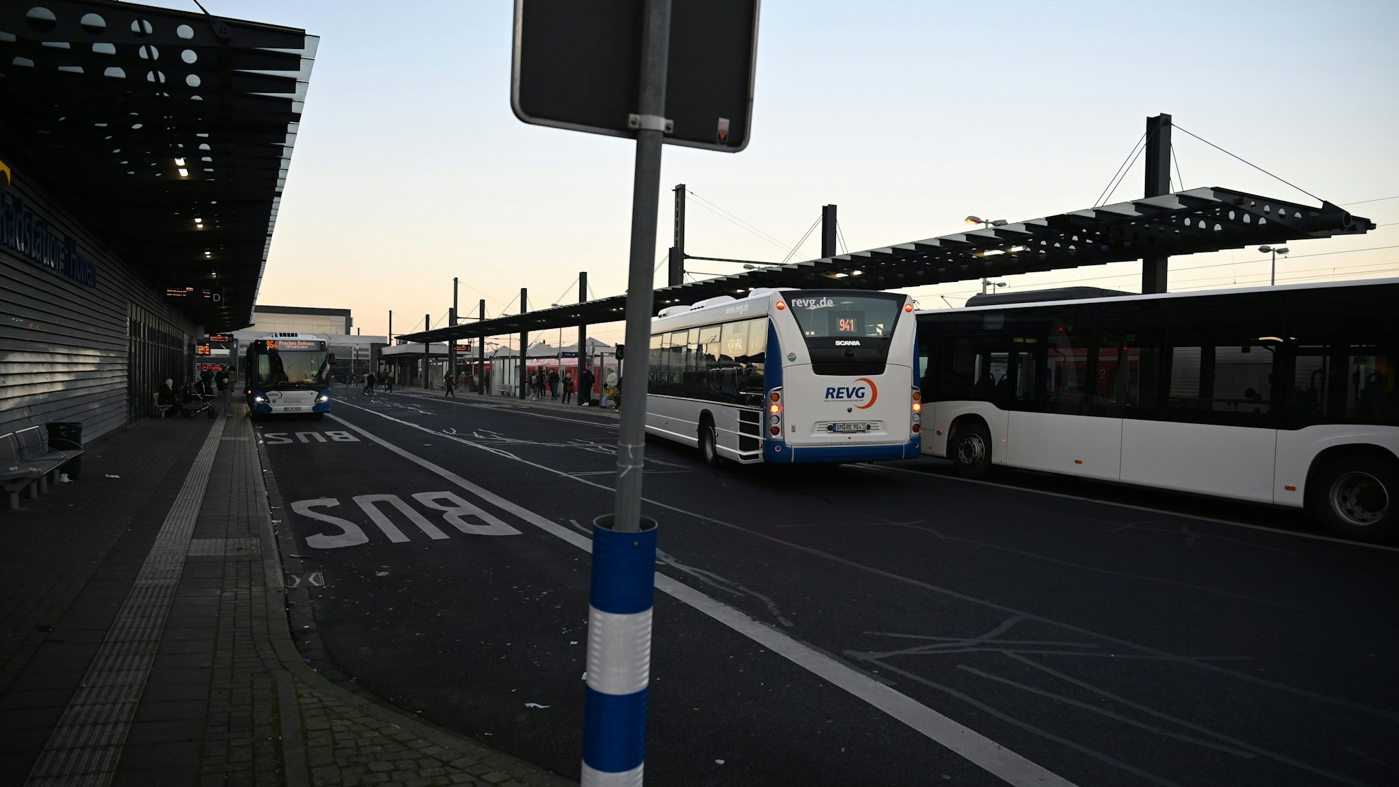 Auf dem Foto ist ein Busbahnhof mit mehreren REVG-Bussen zu sehen.