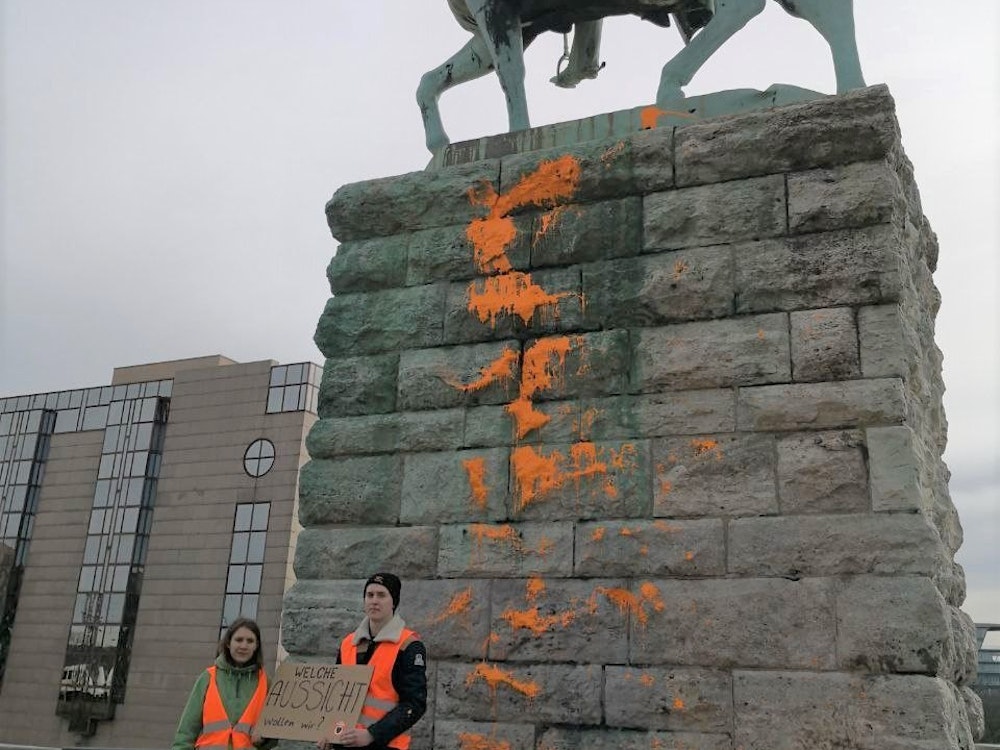Orange Farbe über das Reiterstandbild an der Hohenzollernbrücke in Köln.