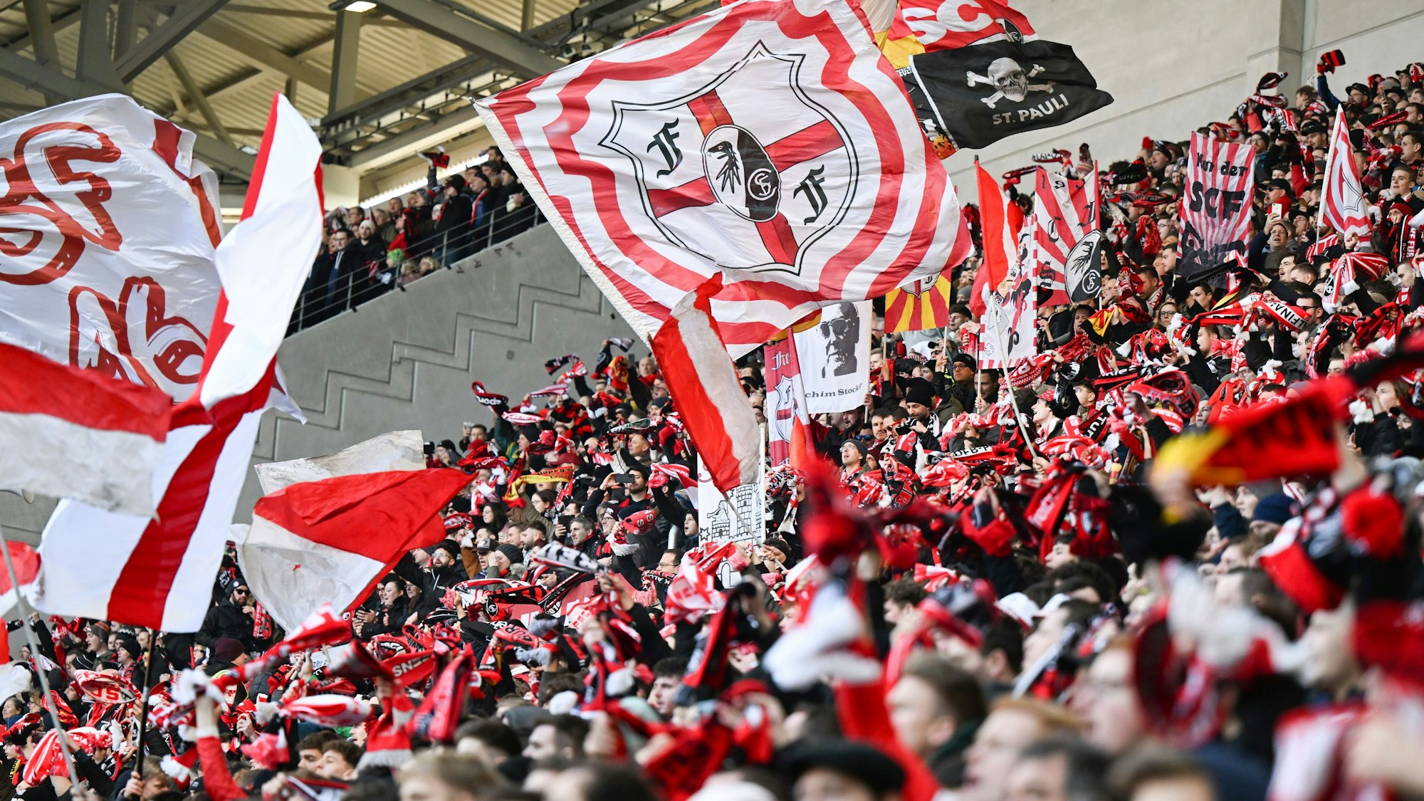 Fans des SC Freiburg beim Spiel des SC Freiburg gegen den VfB Stuttgart mit Schals und Fahnen.