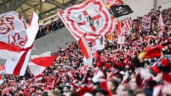 Fans des SC Freiburg beim Spiel des SC Freiburg gegen den VfB Stuttgart mit Schals und Fahnen.