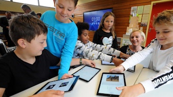 Schulkinder mit iPads im Unterricht.
