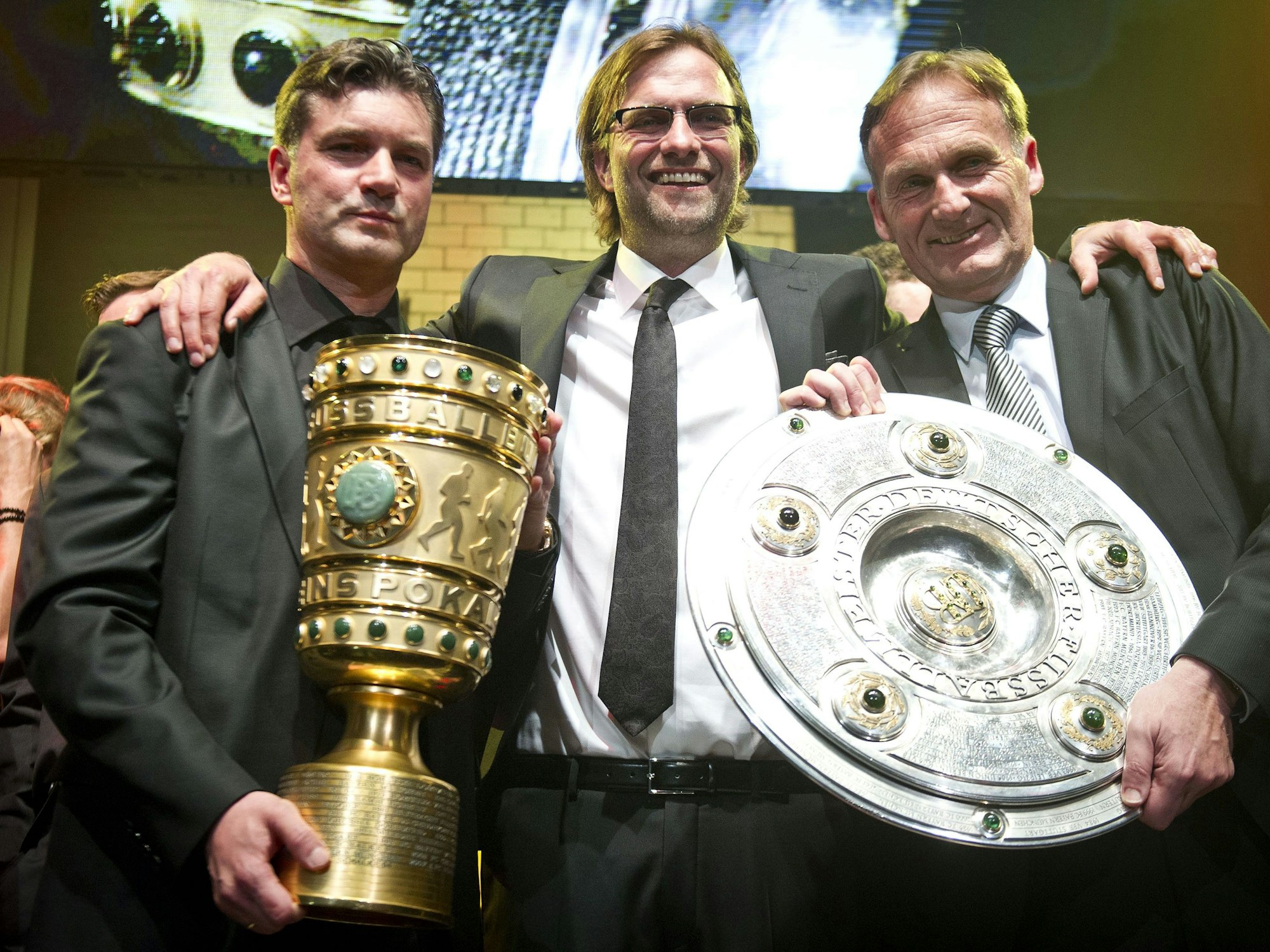 Sportdirektor Michael Zorc (v.l.), Trainer Jürgen Klopp und Geschäftsführer Hans-Joachim Watzke posieren mit dem DFB-Pokal und der Meisterschale.