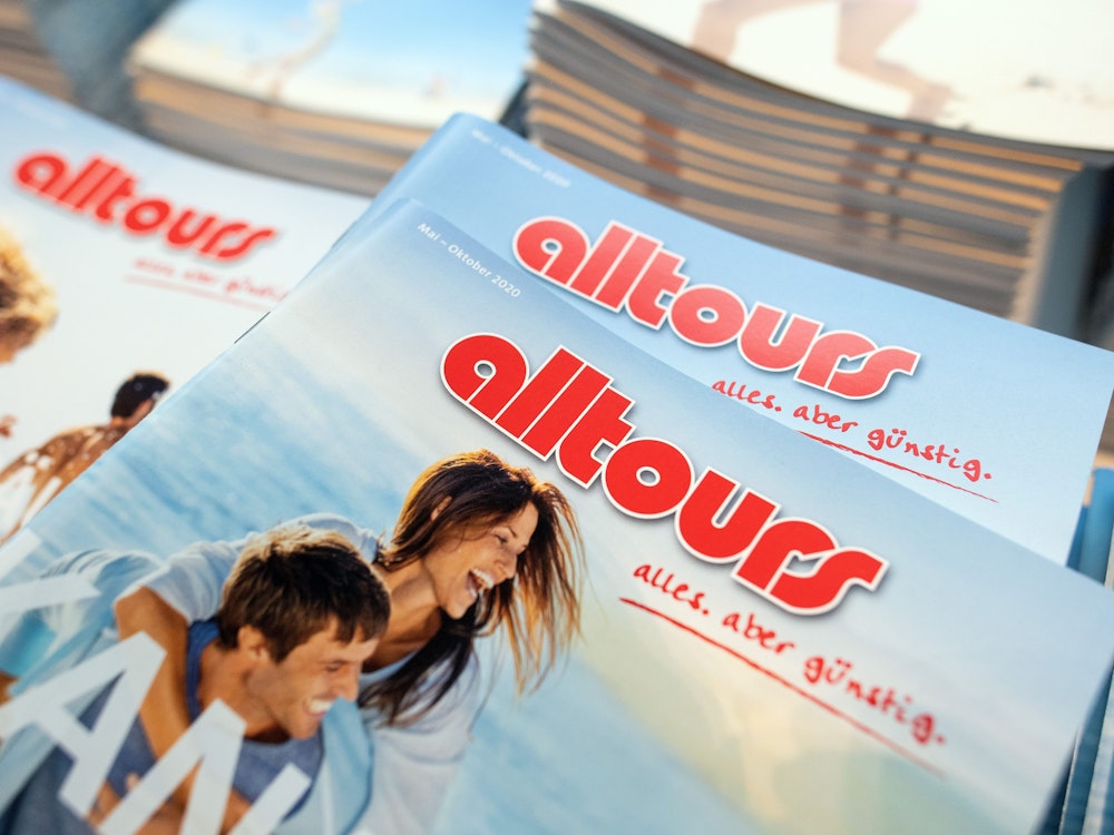 Ein Reisemagazin des Reiseveranstalters Alltours mit zwei lachenden Personen am Meer.
