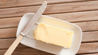 Ein Stück Butter und ein Messer liegen auf einem Teller. 
