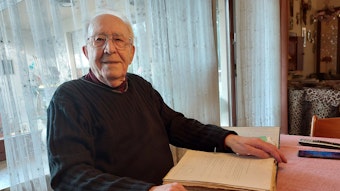 Karl-Heinz Oellig sitzt an einem Tisch und hat einen Ordner mit Dokumenten vor sich liegen.