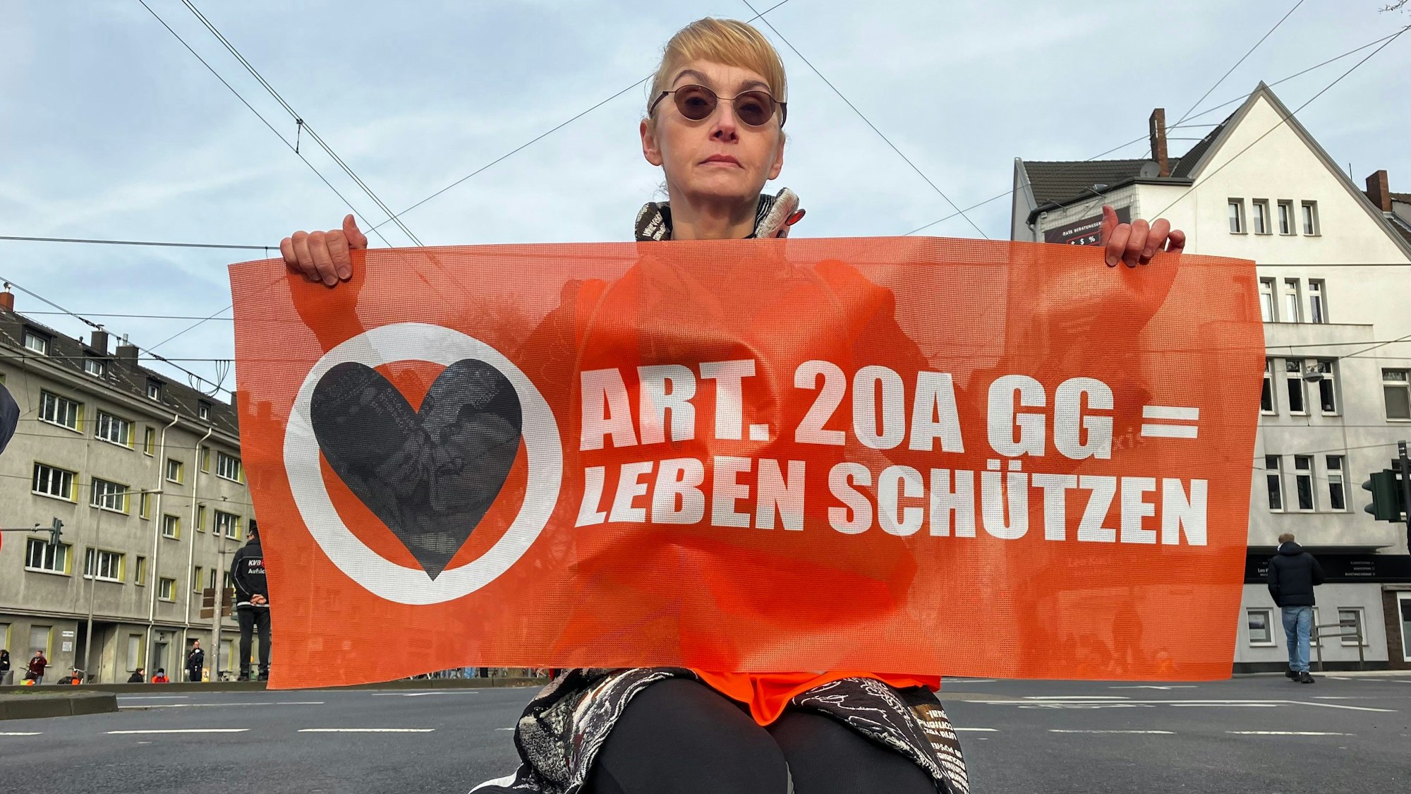 Eine Klima-Aktivistin sitzt auf einer Straße in Köln.
