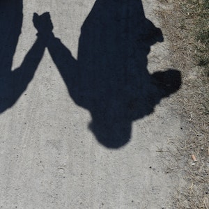 Der Schatten eines händchenhaltenden Pärchens ist am 08. Juni 2014 in München (Bayern) im Englischen Garten auf einem Weg zu sehen.