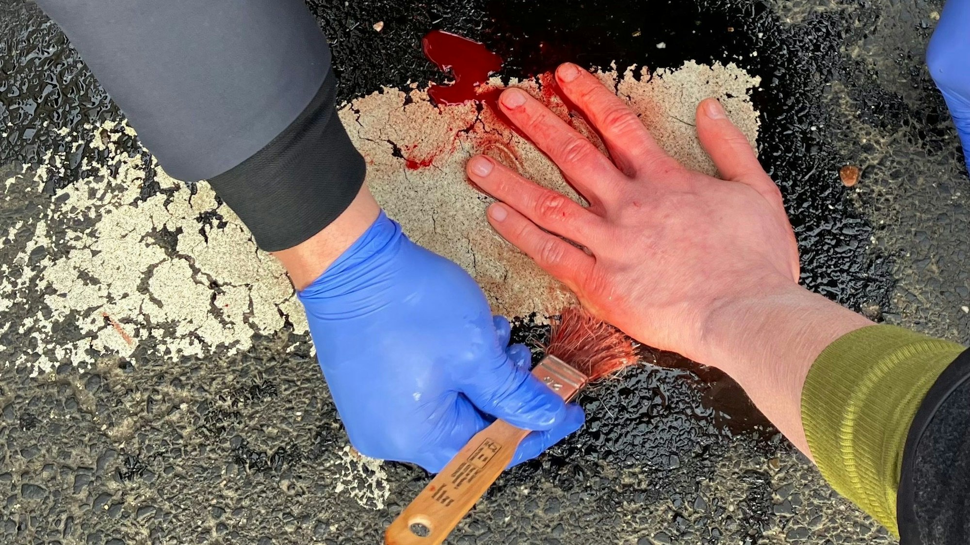 Die Hand eines Klima-Aktivisten wird vom Asphalt einer Straße in Köln mit Öl gelöst. (Symbolbild)
